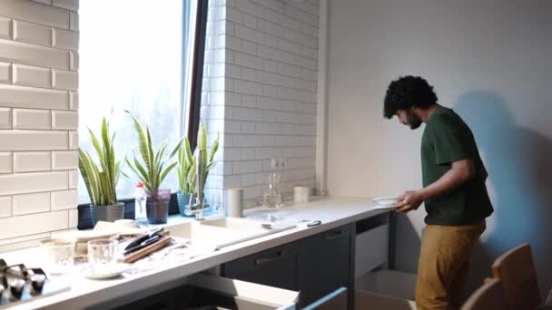 Серьёзный Кудрявый Индеец Кладёт Посуду Шкаф Дома — стоковое видео