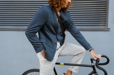 Ginger european man wearing jacket riding on bicycle at city street