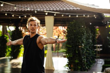 Young curly white man doing workout and stretching his body outdoors