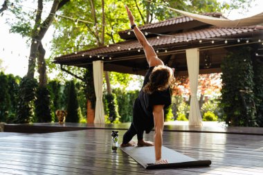 Young ginger curly man doing exercise during yoga practice outdoors