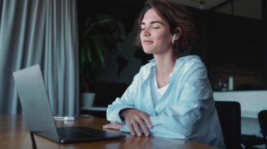 Smiling brunette woman designer talking by video call on laptop in the office