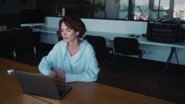Confident brunette woman designer talking by video call on laptop in the office