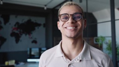 Cheerful man with piercing and dyed blond hair looking at the camera in the office