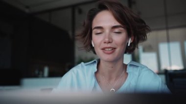 Lovely brunette woman designer talking by video call on laptop in the office