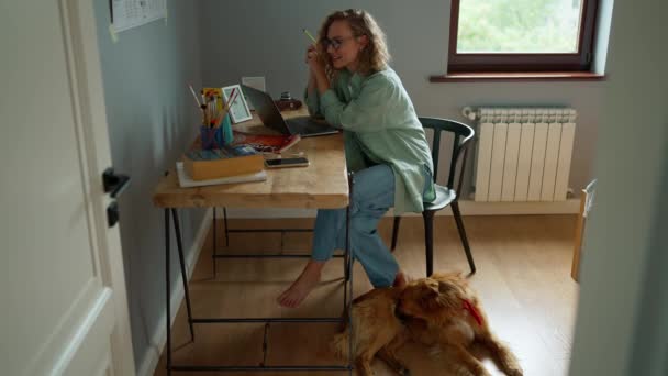 Lächelnde Gelockte Frau Arbeitet Laptop Während Ihr Hund Hause Auf — Stockvideo