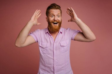 Ginger white man with beard expressing surprise at camera isolated over pink background