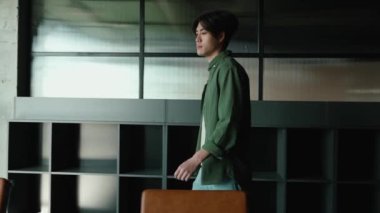 Pozitif esmer Asyalı adam ortak çalışma odasındaki bir masada dizüstü bilgisayarla çalışmaya başlıyor.