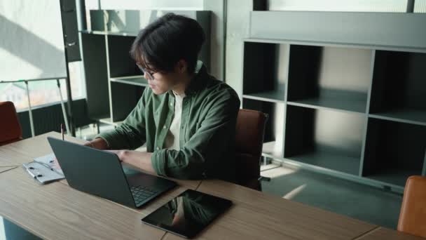 Meditativ Brunett Asiatisk Man Glasögon Arbetar Bärbar Dator Och Skriver — Stockvideo