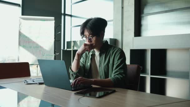 Pensativo Morena Asiático Hombre Gafas Trabajando Ordenador Portátil Escritorio Una — Vídeos de Stock