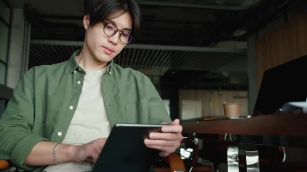 Gai Asiatique Homme Dans Lunettes Textos Sur Tablette Dans Bureau — Video