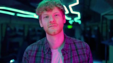 Laughing ginger man gamer walking at the camera after playing RPG video game on a championship. Stylish Neon Cyber Games