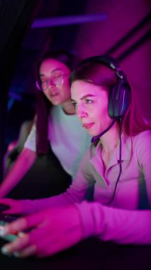Handsome multinational women talking and playing RPG video game on a championship. Stylish Neon Cyber Games