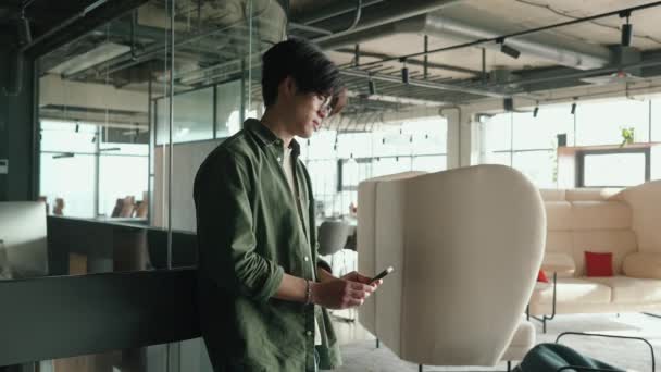 Scontento Bruna Asiatico Uomo Occhiali Digitando Smartphone Working Stanza — Video Stock