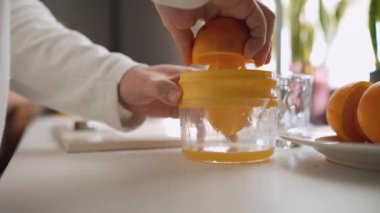 Evdeki mutfakta portakal suyu yapan adamın yakın çekim görüntüsü.