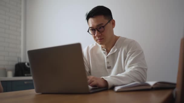 Allvarlig Brunett Asiatisk Man Bär Glasögon Som Arbetar Laptop Köket — Stockvideo