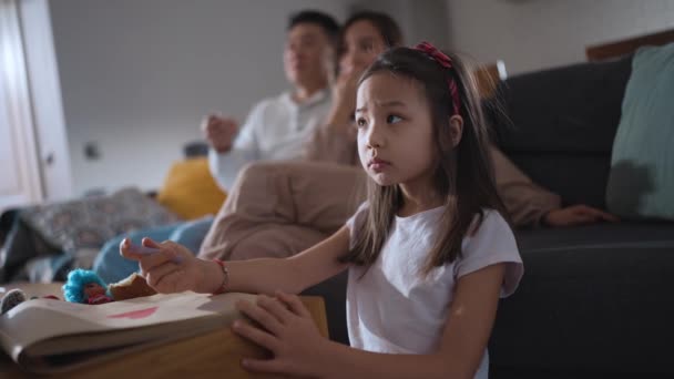 Serieuze Aziatische Jong Meisje Kijken Met Haar Familie Tekening Thuis — Stockvideo