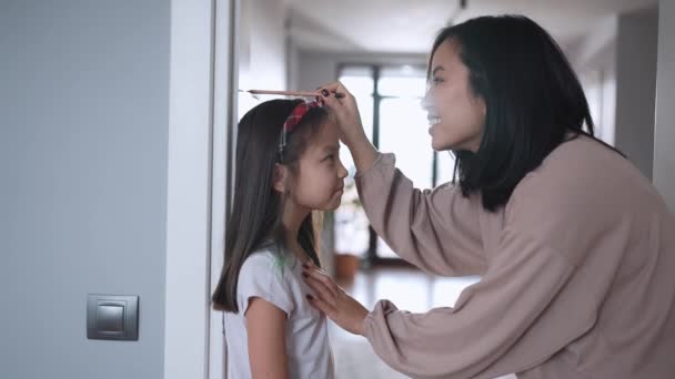 Happy Asian Mom Measures Her Daughter Height Home — Stock Video