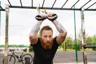 Kızıl sakallı sporcu dışarıda oyun oynarken egzersiz yapıyor.