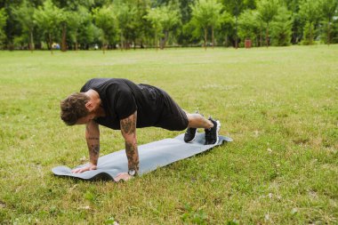 Kızıl sakallı adam parkta yoga yaparken egzersiz yapıyor.