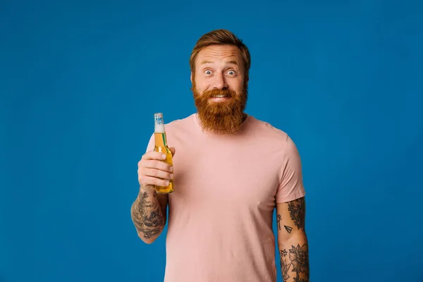 Портрет Взволнованного Рыжего Бородатого Мужчины Держащего Пиво Фоне Синей Студии — стоковое фото