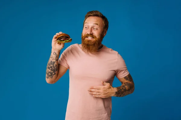 Fehér Éhes Szakállas Ember Eszik Burger Elszigetelt Kék Háttér — Stock Fotó