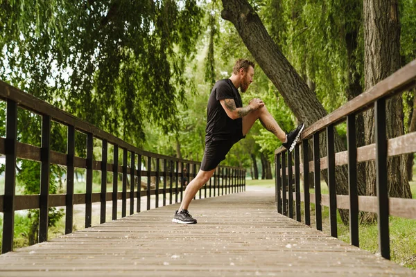 Young Handsome Tattooed Bearded Man Stretching His Leg Wooden Railing — Stock Photo, Image
