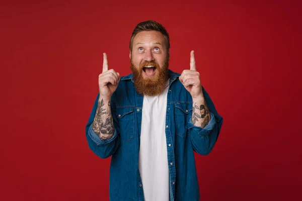 Взрослый Рыжий Бородатый Татуированный Энтузиаст Открытым Ртом Указывает Смотрит Вверх — стоковое фото