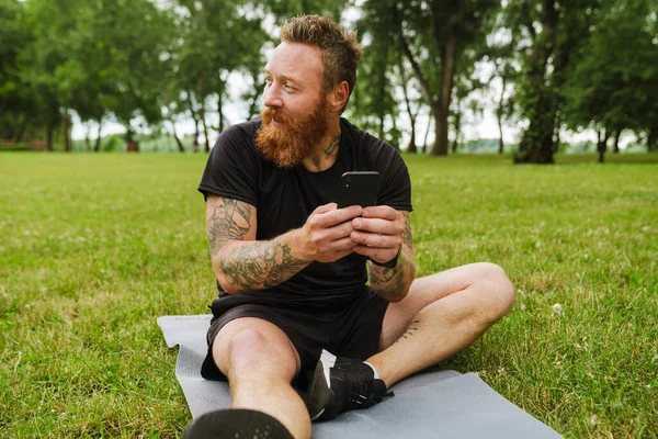 Ginger Barbudo Homem Usando Celular Durante Prática Ioga Parque Livre — Fotografia de Stock
