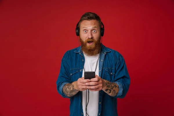 Kızıl Saçlı Kulaklıklı Müzik Dinleyen Kırmızı Arka Planda Izole Edilmiş — Stok fotoğraf