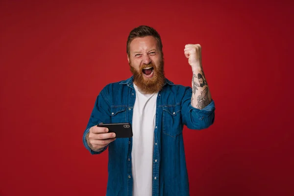 Ginger Excited Man Gesturing While Playing Game Cellphone Isolated Pink — Stock Photo, Image