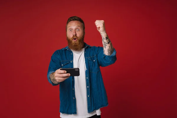 Ginger Excited Man Gesturing While Playing Game Cellphone Isolated Pink — Stock Photo, Image
