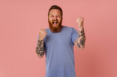 Kızıl beyaz adam çığlık atıyor ve kazanan jest yapıyor pembe arka planda izole edilmiş