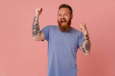 Kızıl beyaz adam çığlık atıyor ve kazanan jest yapıyor pembe arka planda izole edilmiş