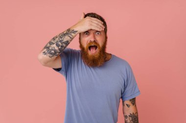 Kızıl heyecanlı sakallı adam, pembe arka planda gözlerini kapatırken çığlık atıyor.