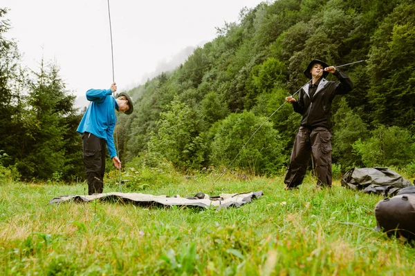 年轻的白种人在山林徒步旅行时 身穿远足装备搭起帐篷 — 图库照片