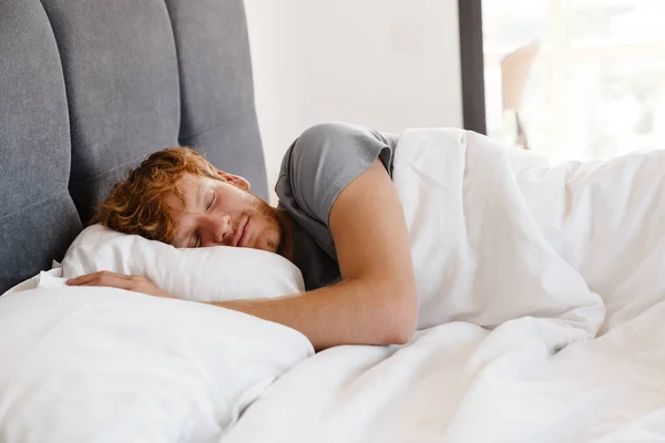 Evdeki Yatakta Gri Tişörtlü Uyuyan Kızıl Saçlı Genç Adamın Portresi — Stok fotoğraf
