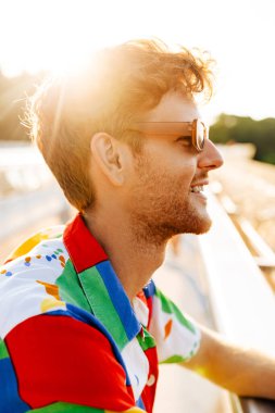 Güneş gözlüklü ve renkli gömlekli yakışıklı bir adamın profil portresi.