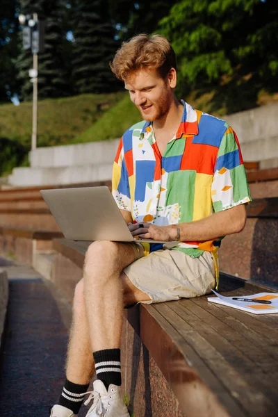 Mladý Pohledný Stylový Usměvavý Muž Pracující Laptopem Zatímco Sedí Zkříženýma — Stock fotografie