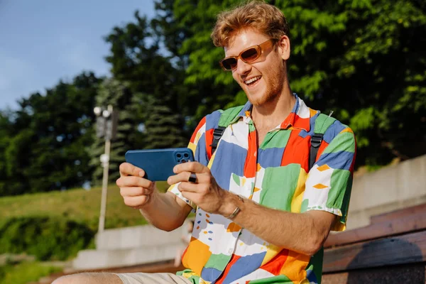 Mladý Pohledný Stylový Usměvavý Muž Slunečních Brýlích Hrát Mobilní Hru — Stock fotografie