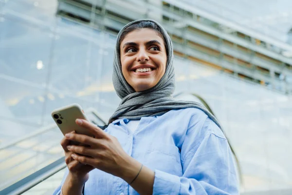 Young Muslim Woman Wearing Headscarf Using Cellphone While Standing Escalator — Stock Photo, Image