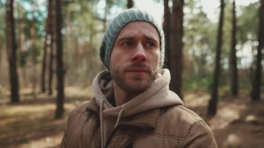 Şapkalı kendine güvenen adam ormana bakıyor.