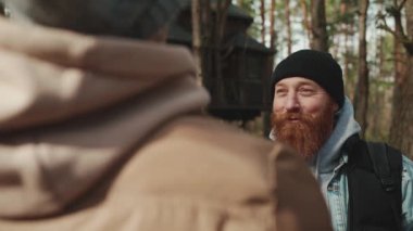 Pozitif sakallı kızıl saçlı yürüyüşçü ormanda arkadaşıyla konuşuyor.