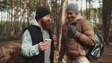 İki mutlu yürüyüşçü arkadaş konuşuyor ve haritada yolu arıyorlar telefonda ormanda bir sırt çantasıyla.