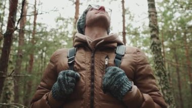 Şapkalı memnun turist ormana bakıyor.