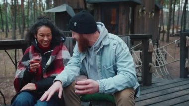 Çok uluslu bir çift ormanda konuşuyor ve şarap içiyor.