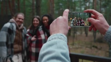 Erkek, telefonuyla ormandaki çok uluslu arkadaşlarının fotoğraflarını çekiyor.