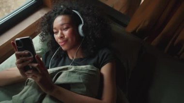 Ormandaki bir modüler evde müzik dinleyen ve telefonla mesajlaşan komik Afrikalı kadın.