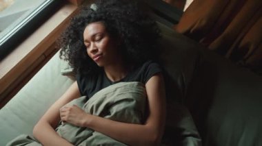 Yakışıklı Afrikalı kadın uyanır ve pencereden dışarı bakar ormandaki modüler bir evde