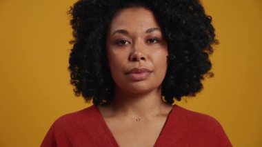 Pozitif Afrikalı kadın sarı stüdyoda kameraya bakıyor.