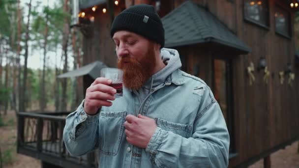 ハンサムな髭を生やした観光客の男が森の中でマルチワインを飲む — ストック動画
